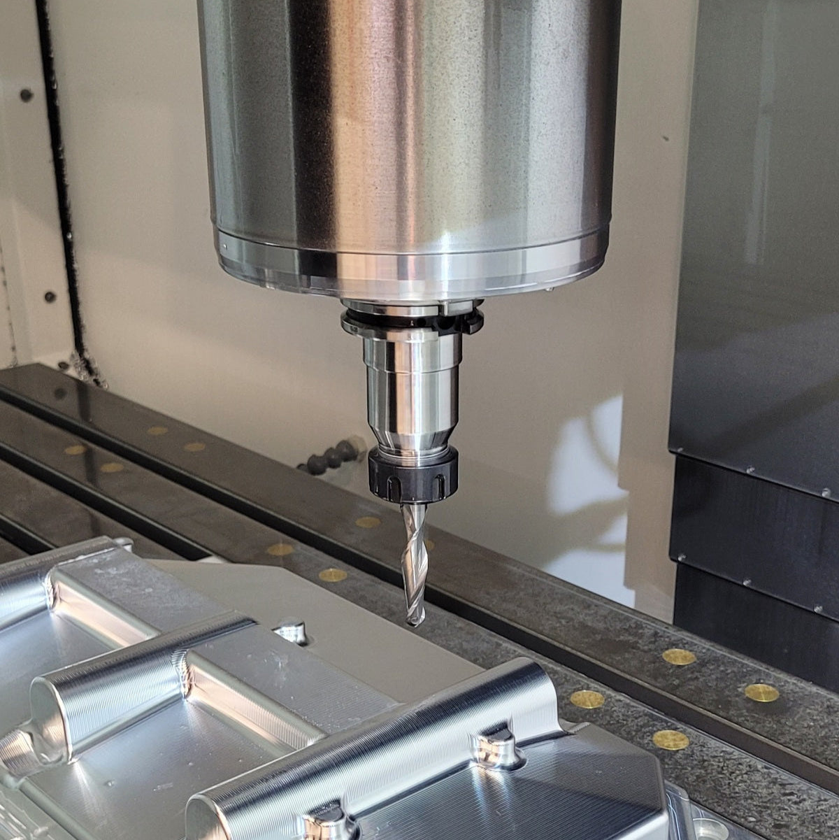 CNC machine tool in operation with a drill bit approaching a workpiece.